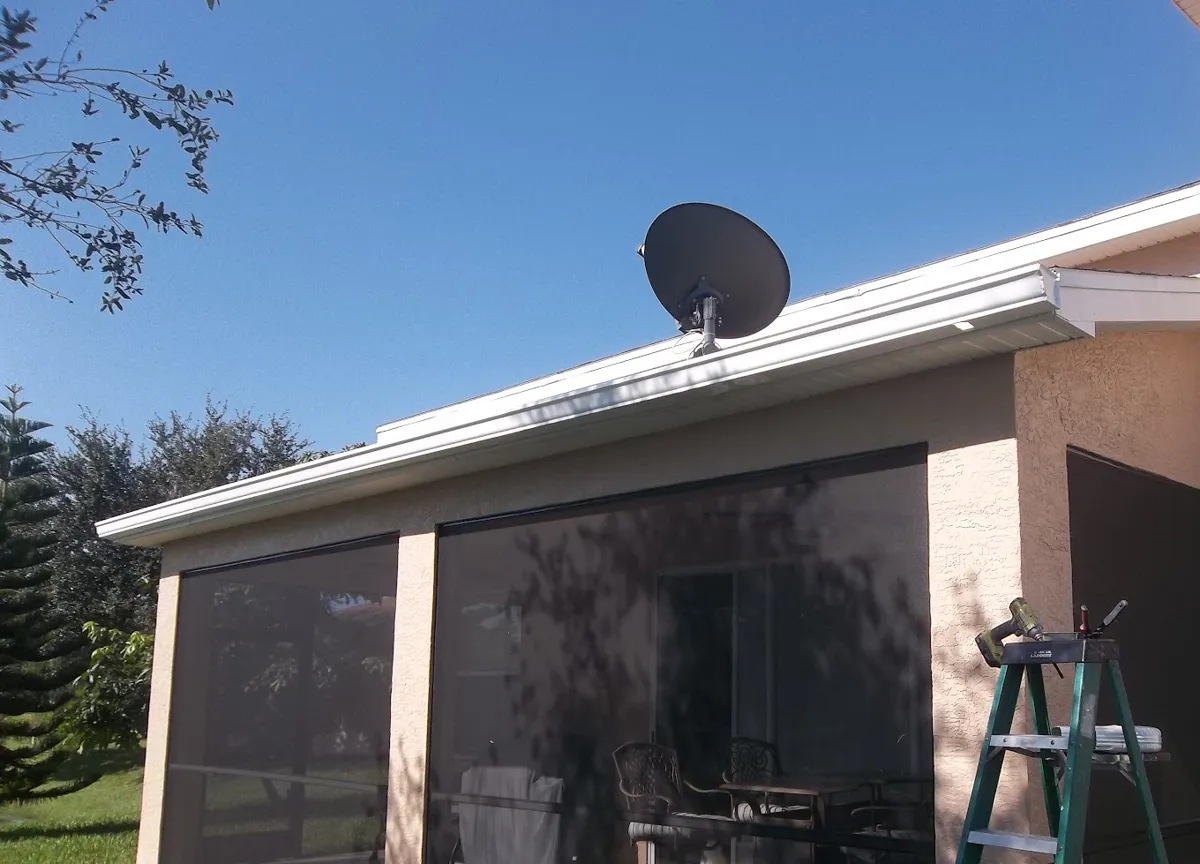 Screened lanai on a single-story stucco home with a white gutter along the roof edge